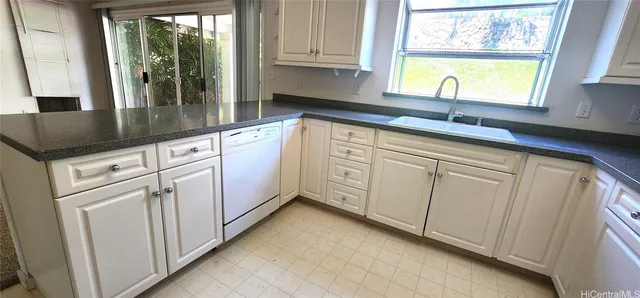 a kitchen with granite countertop white cabinets and a window