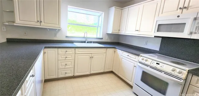 a kitchen with granite countertop white cabinets and a sink