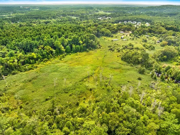 an aerial view of residential houses with outdoor space and trees