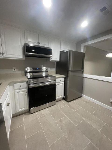 1638 Embassy Drive, Unit 102 West Palm Beach, FL 33401 - Photo 2 of 18 a kitchen with a stove top oven and cabinets