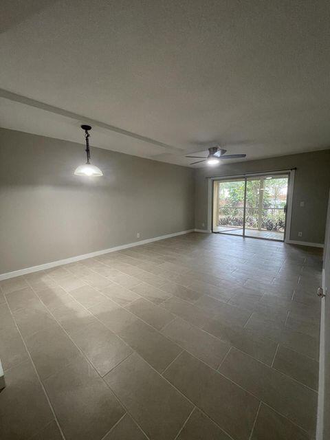 1638 Embassy Drive, Unit 102 West Palm Beach, FL 33401 - Photo 6 of 18 en empty room with windows and chandelier
