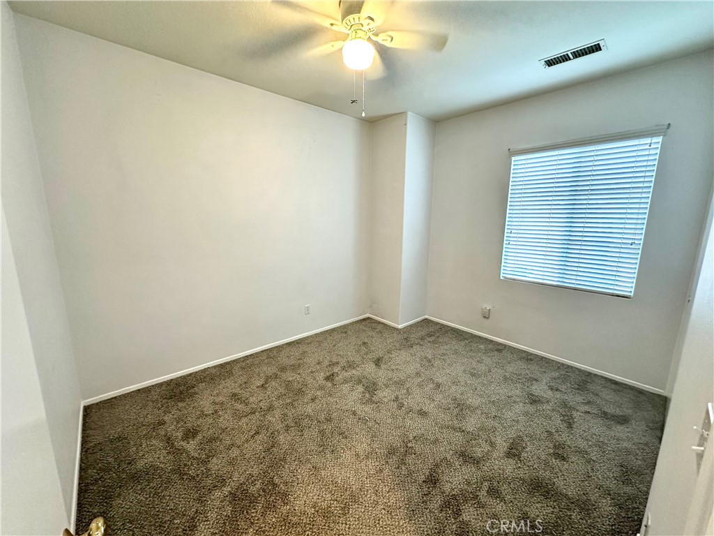 11146 Gardenhurst Court Riverside, CA 92505 - Photo 11 of 16 an empty room with a chandelier fan and windows