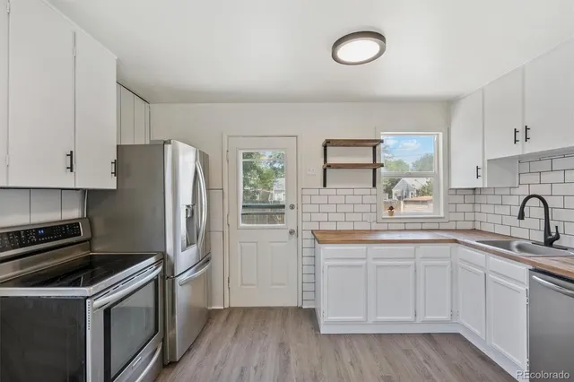 a kitchen with a sink cabinets stainless steel appliances and a window