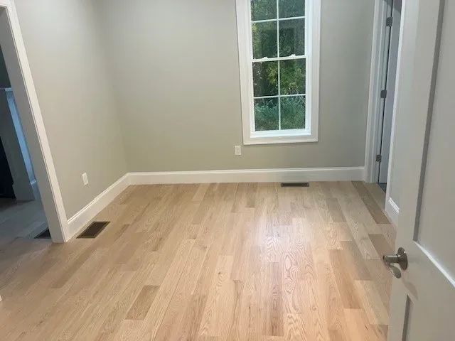 an empty room with wooden floor and windows