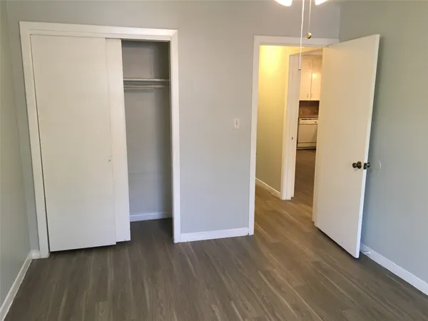a view of an empty room with wooden floor and closet area