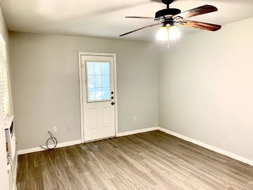 an empty room with wooden floor fan and windows