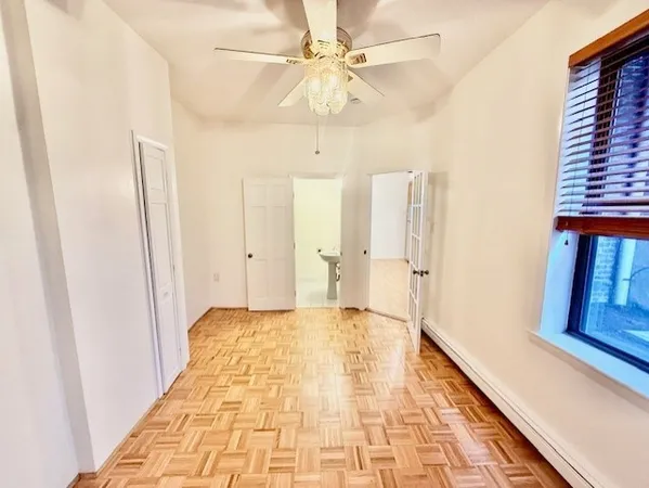 a view of empty room with wooden floor and fan