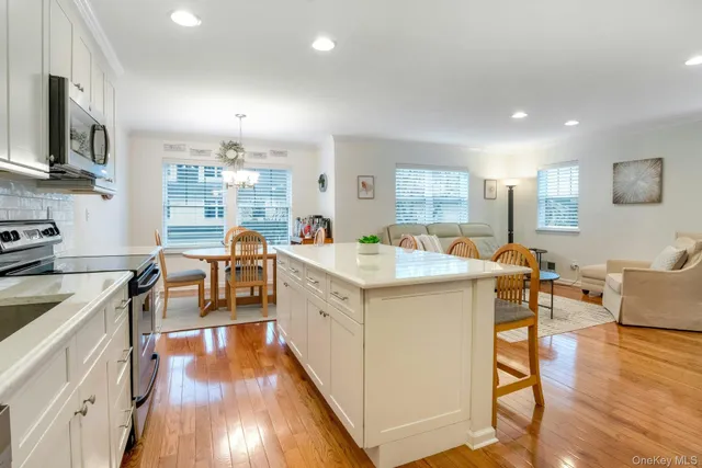 a large white kitchen with lots of counter top space a sink a counter space and stainless steel appliances