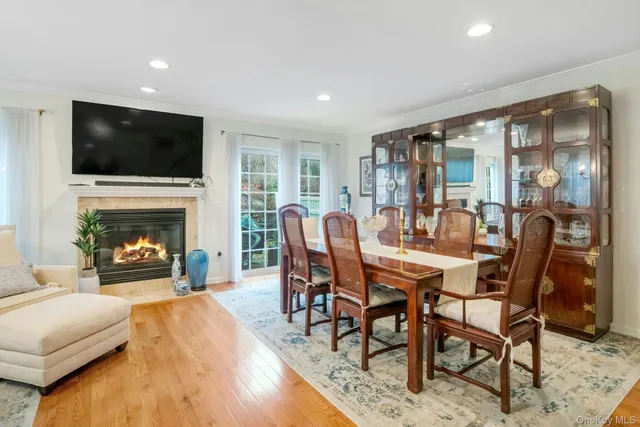 a dining room with furniture wooden floor a flat screen tv a rug and a chandelier