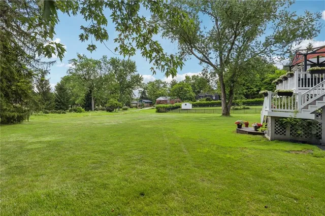 a view of a house with a big yard and large trees