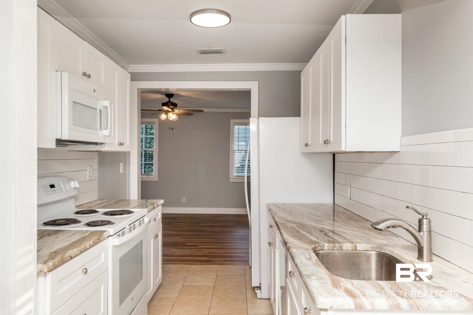 263 Border Drive East Mobile, AL 36608 - Photo 11 of 27 Galley kitchen featuring white cabinetry, light-toned countertops, a stainless steel sink with a gooseneck faucet, a white range, and a white over-the-range microwave
