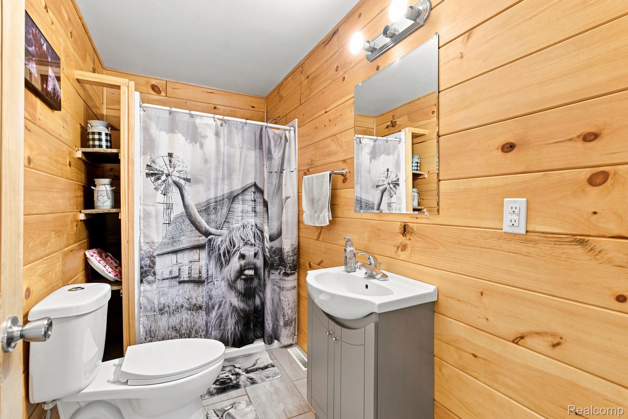 4201 Galbraith Line Road Croswell, MI 48422 - Photo 9 of 39 Room featuring knotty pine paneling, built-in shelving, a shower with curtain, a toilet, and a vanity with a sink