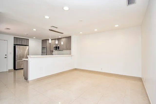 a view of kitchen with refrigerator and white cabinets