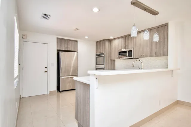 a kitchen with kitchen island a refrigerator sink and stove