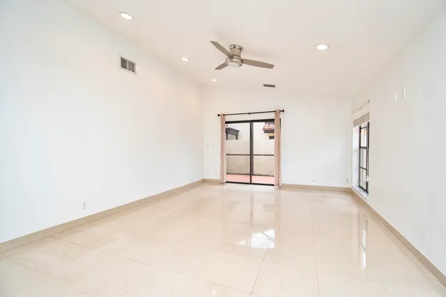 an empty room with windows and ceiling fan