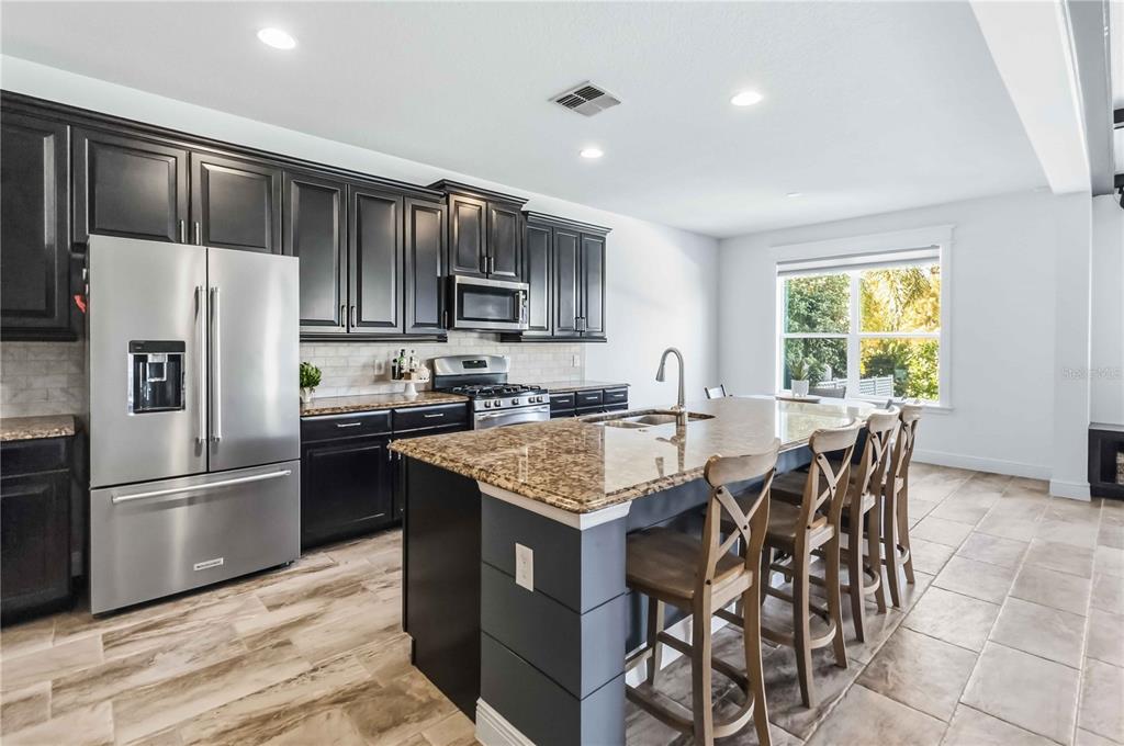 1004 Vinsetta Circle Winter Garden, FL 34787 - Photo 19 of 64 a kitchen with stainless steel appliances granite countertop a refrigerator a sink a stove a dining table and chairs