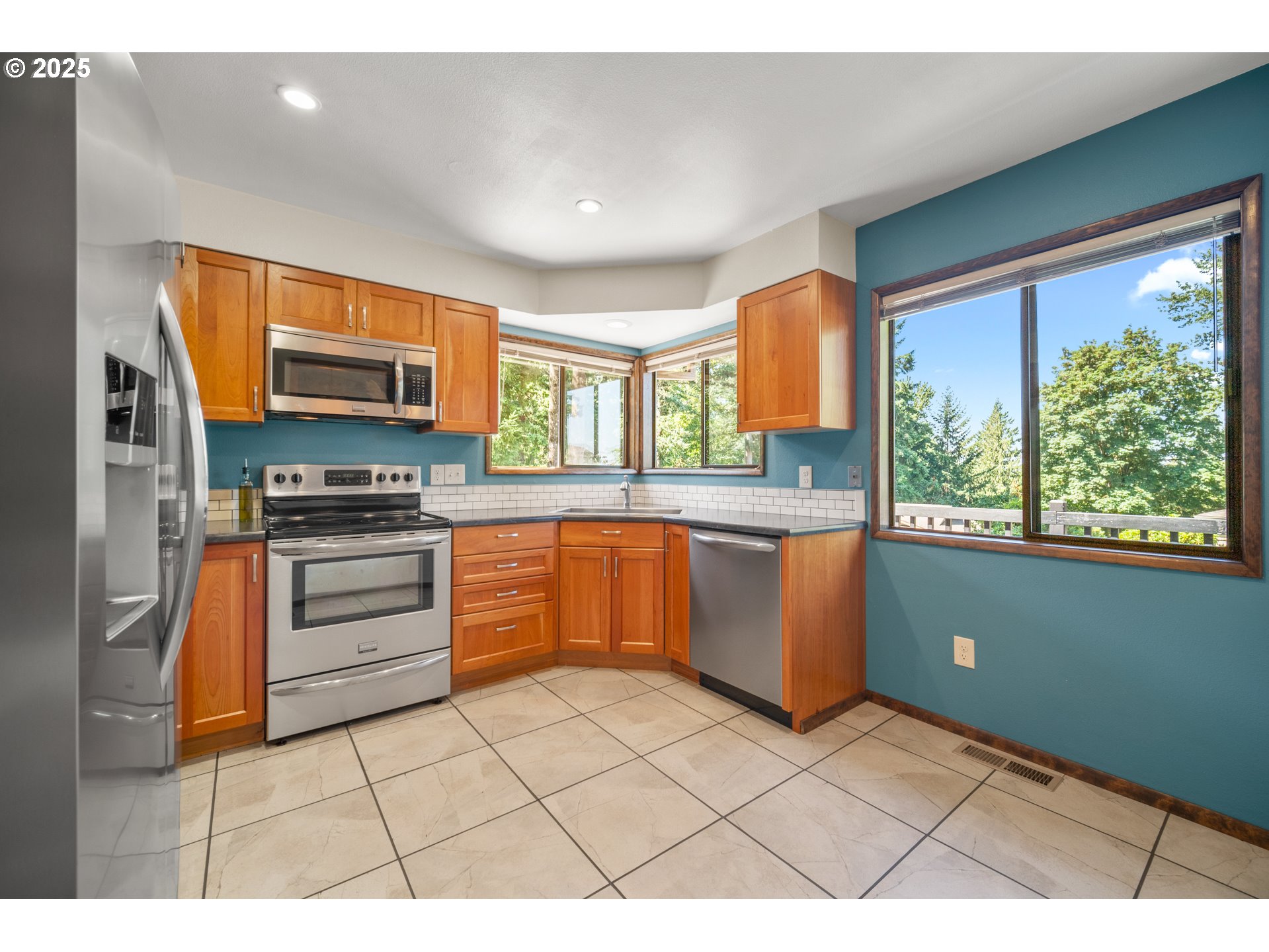 9420 Southeast Carnaby Way Happy Valley, OR 97086 - Photo 11 of 43 a kitchen with stainless steel appliances kitchen island granite countertop a stove a sink and a microwave
