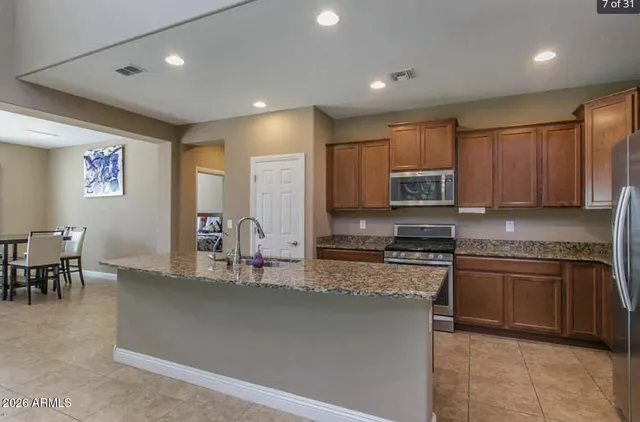 a kitchen with stainless steel appliances granite countertop a stove top oven a sink a dining table and chairs