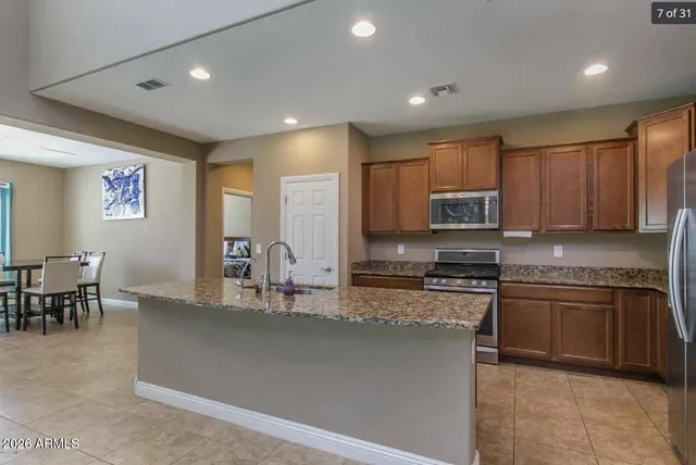 a kitchen with stainless steel appliances granite countertop a stove top oven a sink a dining table and chairs