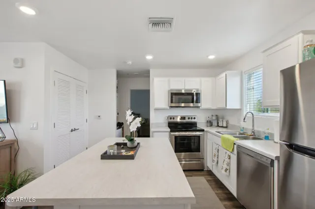 a kitchen with stainless steel appliances a stove a sink a refrigerator a center island and cabinets