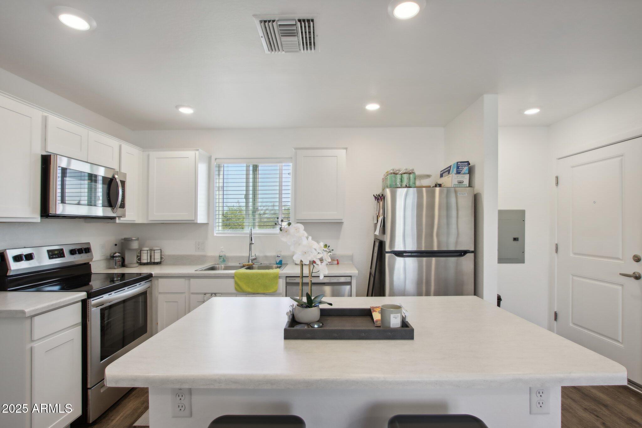 12925 West Greenway Road, Unit 5 El Mirage, AZ 85335 - Photo 7 of 30 a kitchen with a refrigerator a stove a sink and white cabinets
