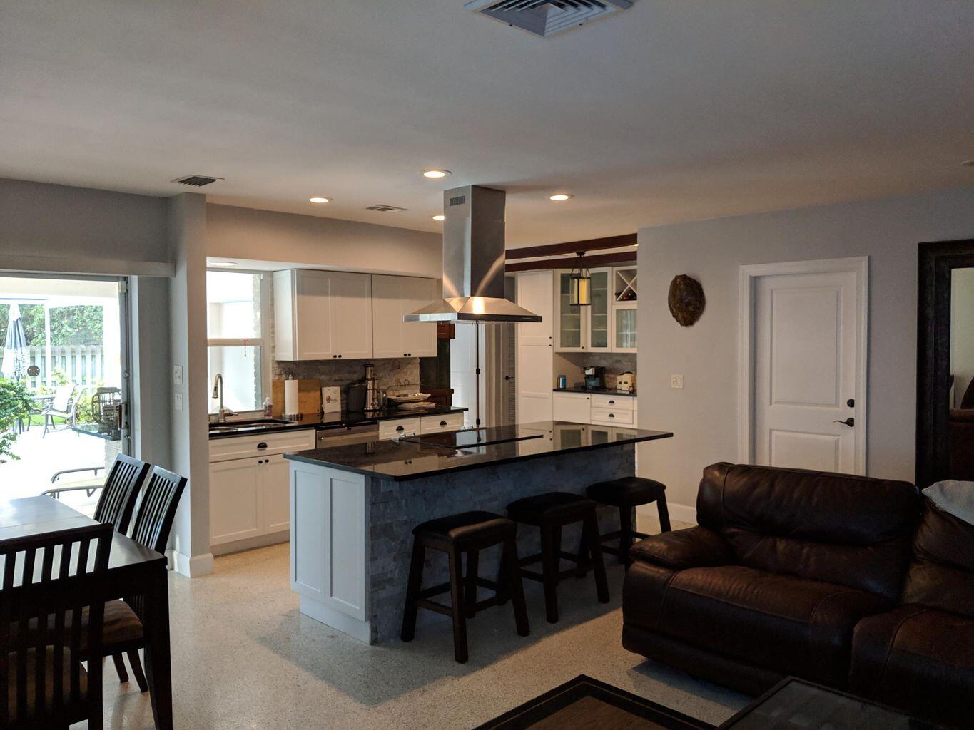 a living room with stainless steel appliances kitchen island granite countertop furniture and a wooden floor