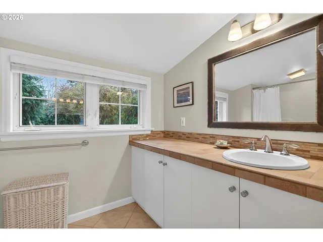 a bathroom with a granite countertop sink a large mirror a and a window