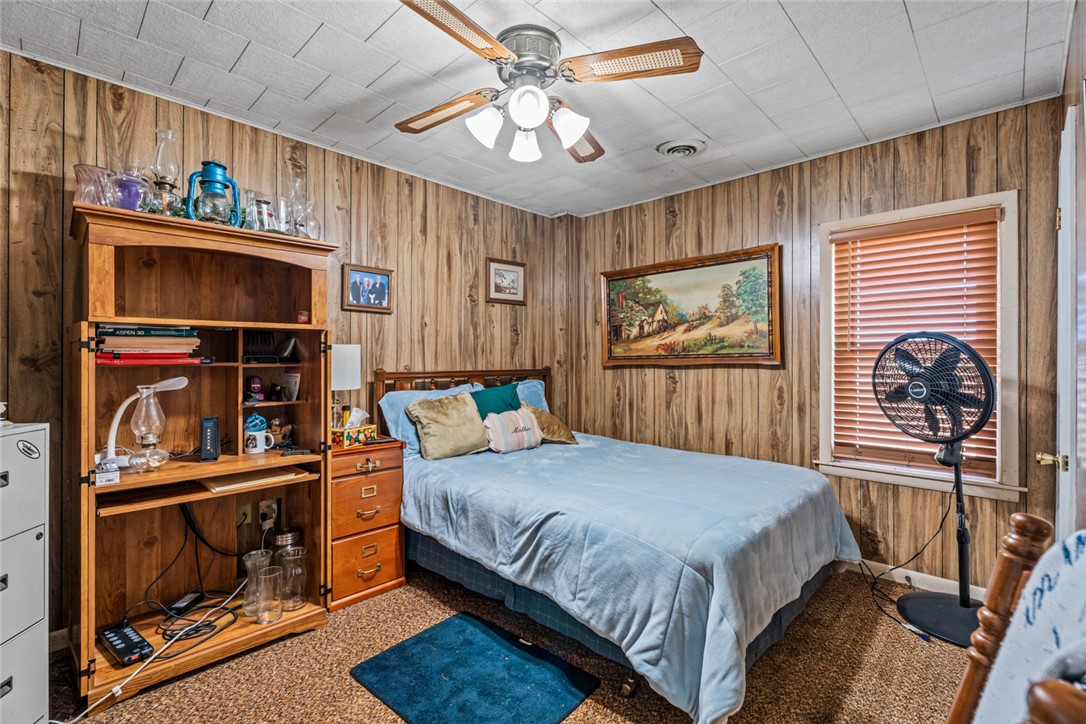 7404 Grubbs-Rex Road Arcanum, OH 45304 - Photo 17 of 40 This cozy bedroom features paneling and a ceiling fan, offering a comfortable and rustic ambiance.