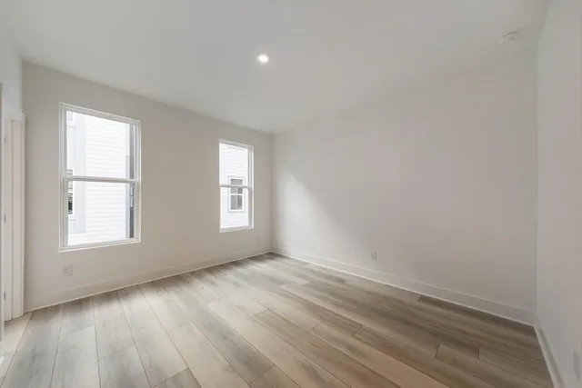 an empty room with wooden floor and windows