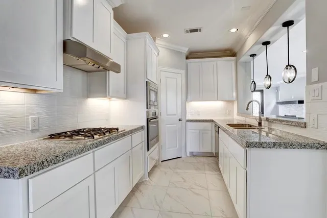 a kitchen with granite countertop a sink stove and cabinets