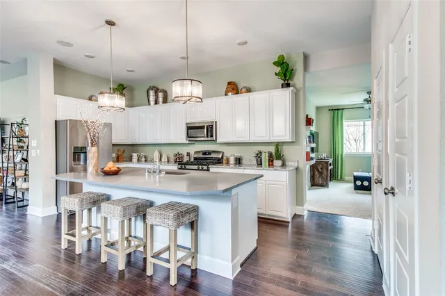 a kitchen with stainless steel appliances white cabinets a sink a stove a refrigerator and wooden floor