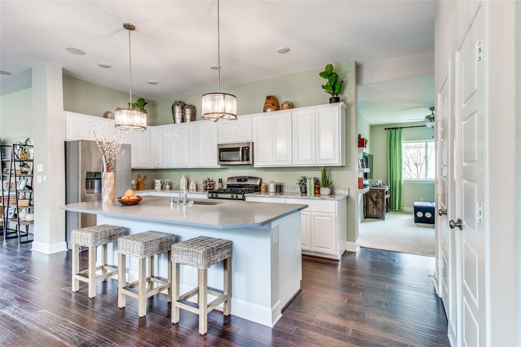 1605 Cedar Crest Drive Forney, TX 75126 - Photo 7 of 26 a kitchen with stainless steel appliances white cabinets a sink a stove a refrigerator and wooden floor