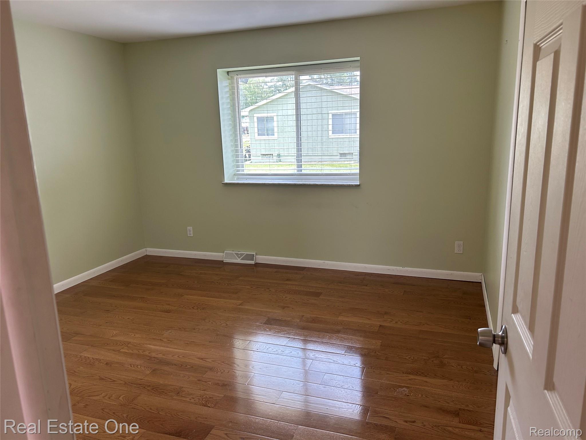 2659 Benstein Road Commerce Township, MI 48382 - Photo 15 of 26 Room featuring wood-finish flooring, light green painted walls, white trim, and a window with blinds