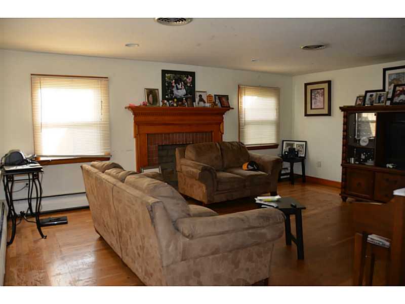 229 Mapleton Street Cranston, RI 02910 - Photo 4 of 9 Living Room. Hardwood floors, multiple windows, brick fireplace both in this room and lower level.