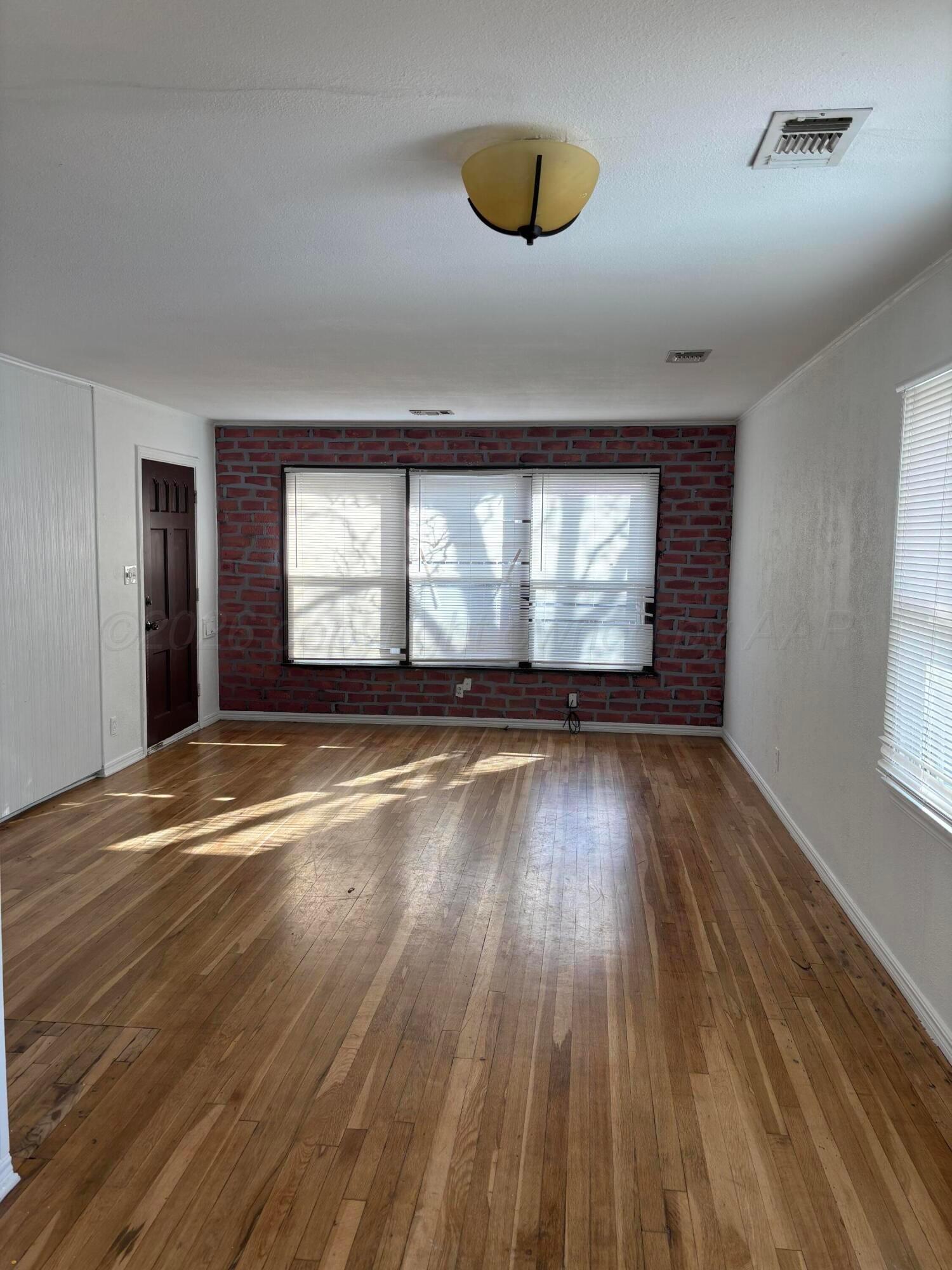4014 Cline Road Amarillo, TX 79110 - Photo 3 of 21 an empty room with wooden floor and windows