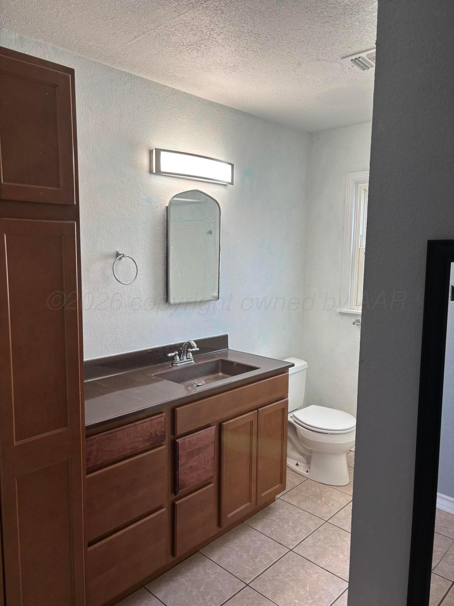 4014 Cline Road Amarillo, TX 79110 - Photo 9 of 21 a bathroom with a toilet a sink a vanity and mirror