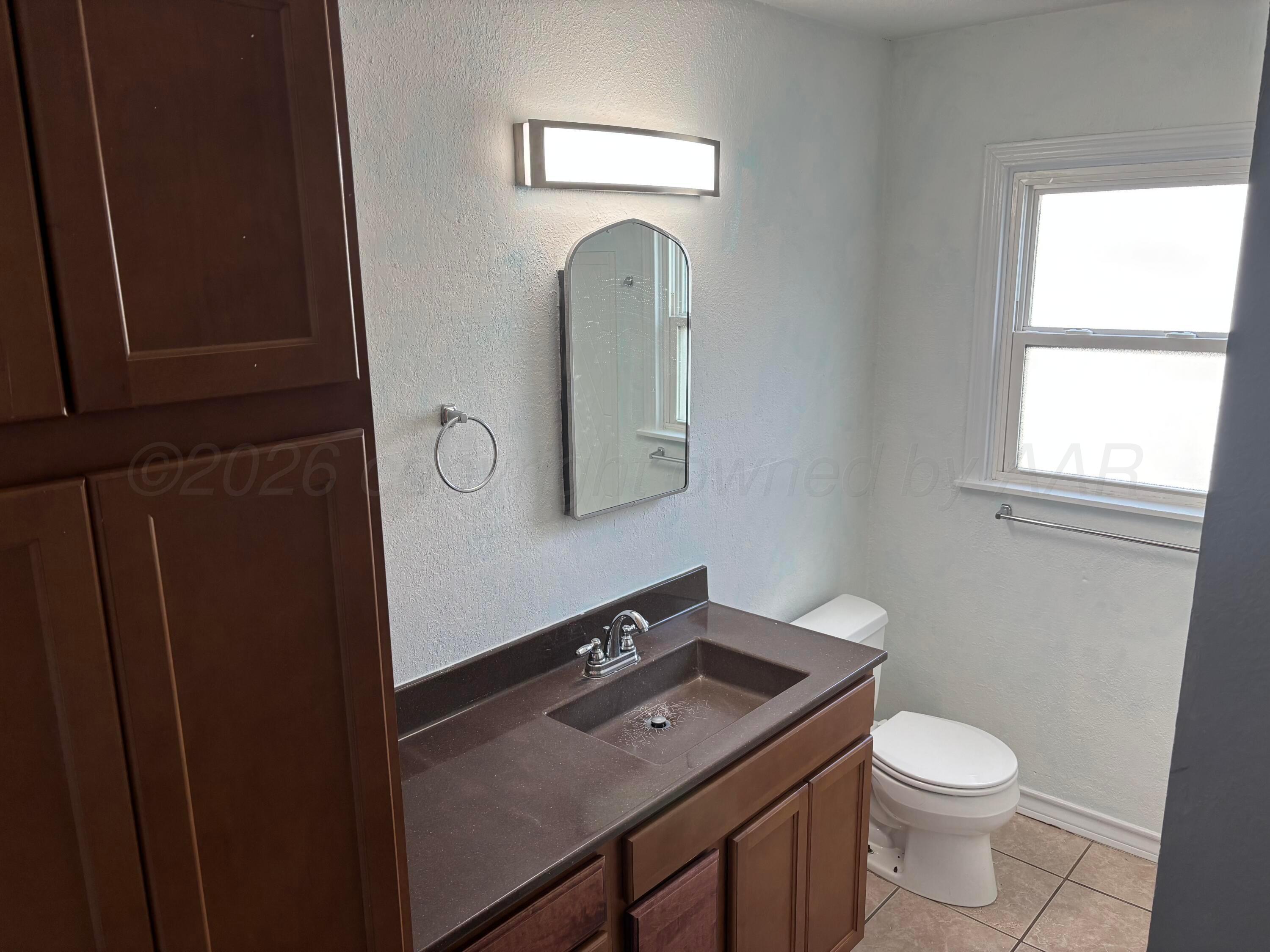 4014 Cline Road Amarillo, TX 79110 - Photo 10 of 21 a bathroom with a toilet sink vanity and mirror