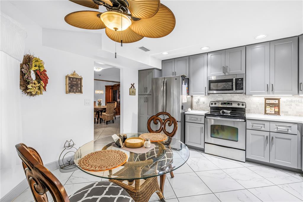 415 Spring Lakes Boulevard, Unit 415D Bradenton, FL 34210 - Photo 15 of 52 a kitchen with stainless steel appliances granite countertop a stove a refrigerator a sink a dining table and chairs with wooden floor