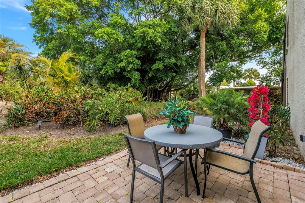 415 Spring Lakes Boulevard, Unit 415D Bradenton, FL 34210 - Photo 34 of 52 a backyard with table and chairs with potted plants and large trees