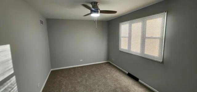 an empty room with a window and a ceiling fan