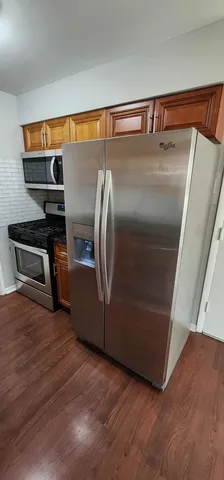 a view of a refrigerator in kitchen and an empty room