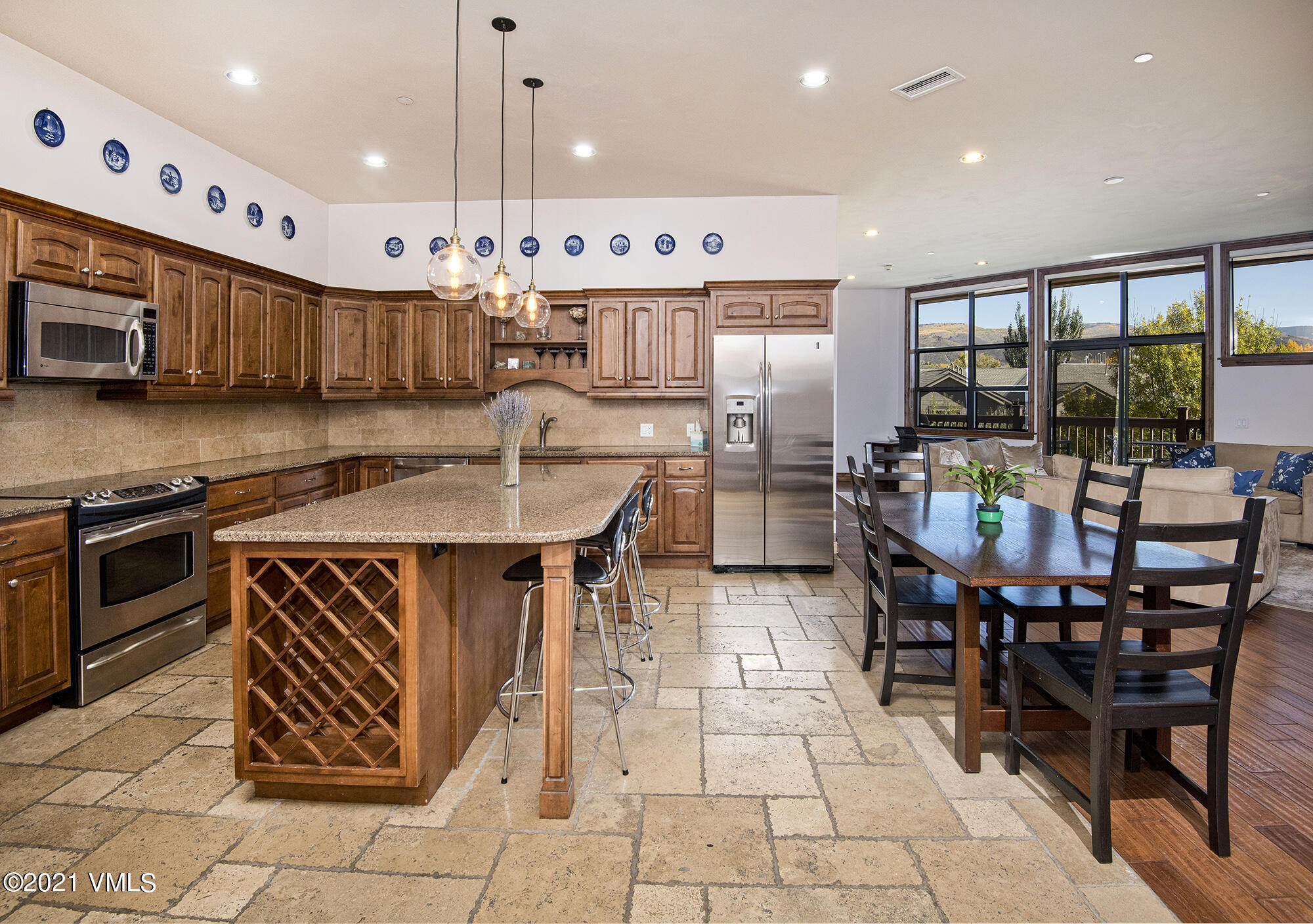 295 Main Street, Unit R201 Edwards, CO 81632 - Photo 3 of 36 a kitchen with stainless steel appliances granite countertop a stove top oven a sink a dining table and chairs with wooden floor