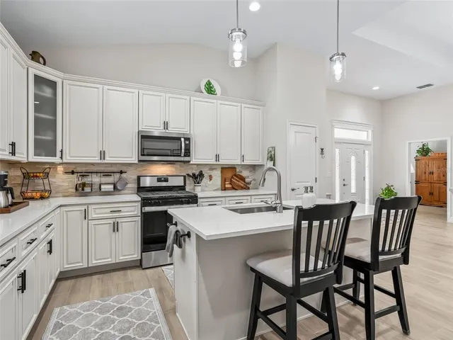 a kitchen with stainless steel appliances granite countertop a sink a stove and cabinets