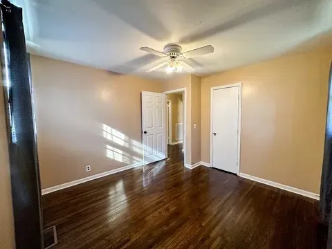 a view of an empty room with window and wooden floor