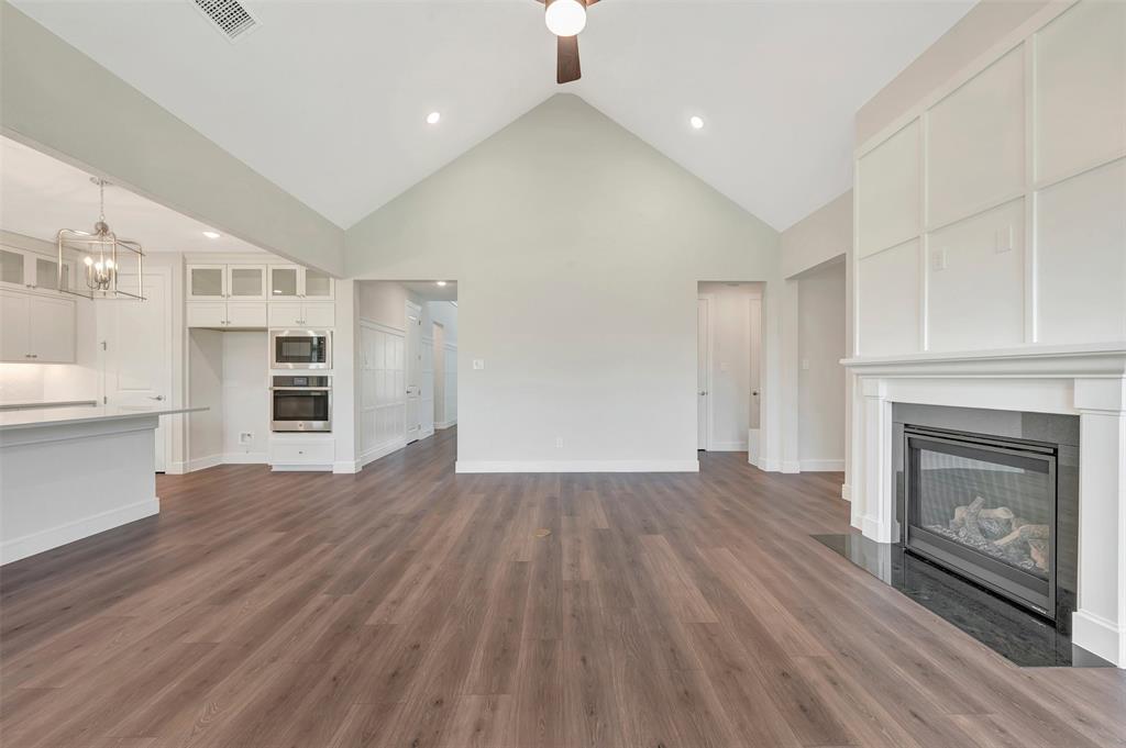 11460 Wulstone Road Fort Worth, TX 76052 - Photo 6 of 40 a view of kitchen and empty room with wooden floor and fireplace