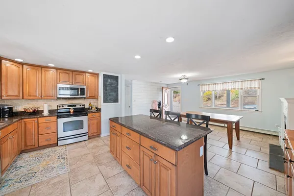 a kitchen with stainless steel appliances granite countertop a stove top oven a sink dishwasher a dining table and chairs with wooden floor
