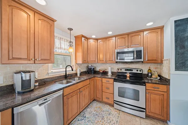 a kitchen with stainless steel appliances granite countertop a sink a stove a microwave and cabinets
