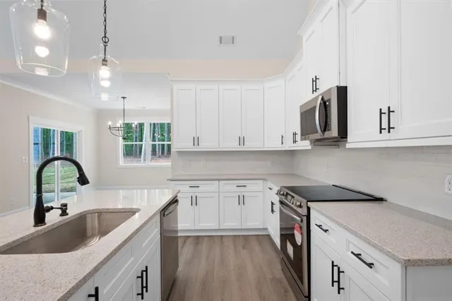 a kitchen with granite countertop a sink white cabinets and window