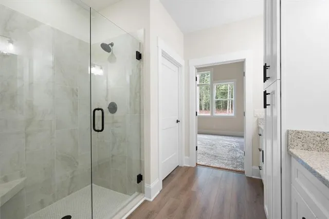 a bathroom with a granite countertop shower a sink and a mirror