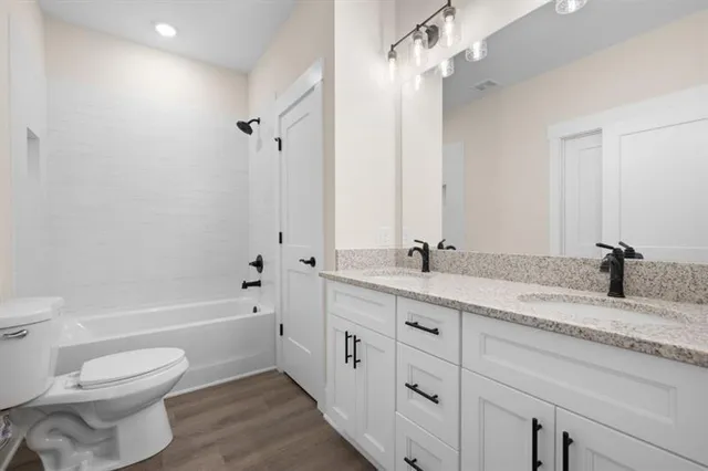 a bathroom with a granite countertop sink a toilet and a bathtub